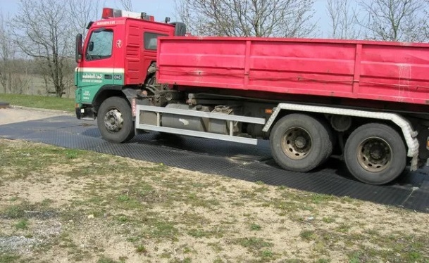 Czerwona ciężarówka wywrotka stoi na płytach WS MudGuard zabezpiczających ziemię